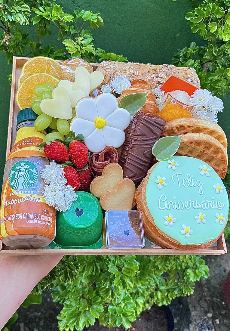 Cesta de café da manhã com frutas, flores, biscoitos e doces.
